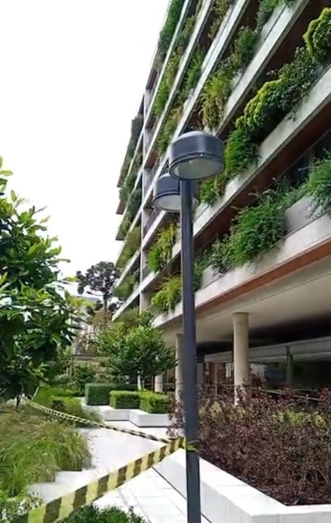 Fachada de condomínio de alto padrão coberta por floreiras e jardins verticais
