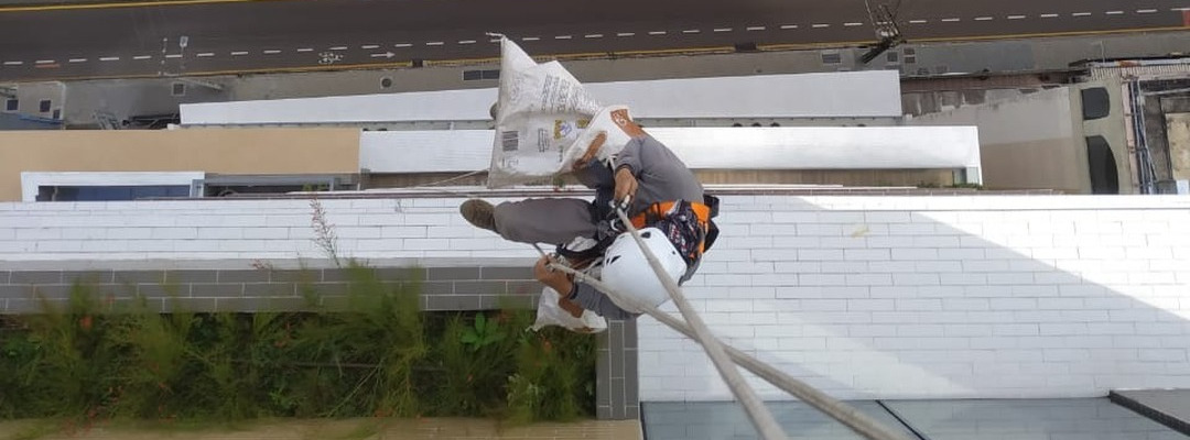 Manutenção e poda de floreiras em fachada predial via rapel